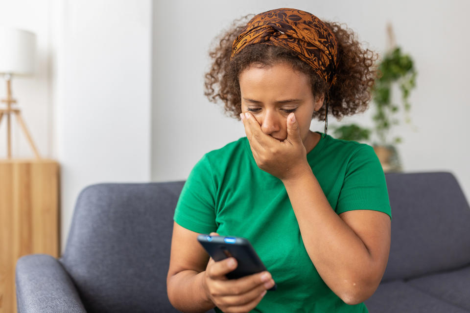 Frustrated young adult woman reading message on smartphone