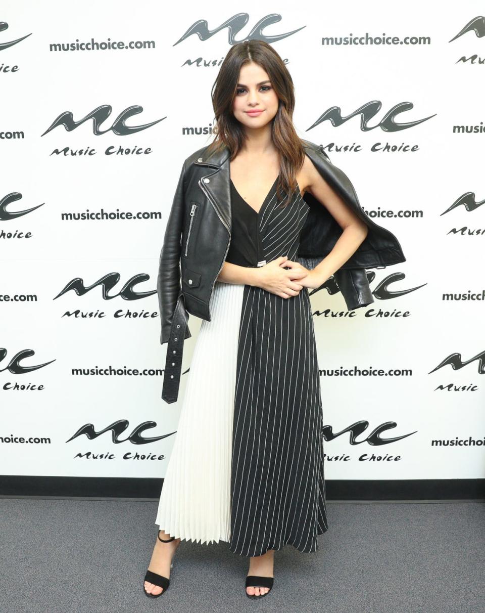 <p>Selena visited Music Choice in a monochrome panelled dress and a leather jacket, June 2017. </p>