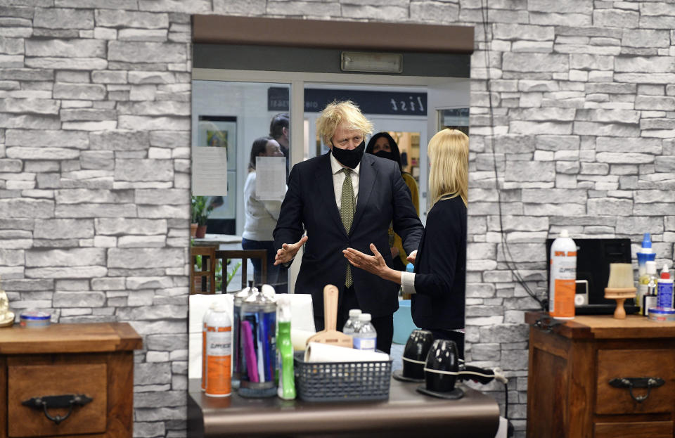 Britain's Prime Minister Boris Johnson in Lemonheads Barber shop during a visit to Lemon Street Market in Truro, England, Wednesday, April 7, 2021 to see how they are preparing to reopen ahead of Step 2 of the roadmap on Monday. Johnson has confirmed that businesses from barbers to bookstores will be allowed to reopen next week and that Britain's slow but steady march out of a three-month lockdown remains on track. (Justin Tallis/Pool Photo via AP)