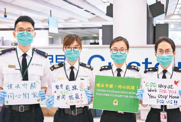 海關人員在機場手持標語呼籲市民同心抗疫。