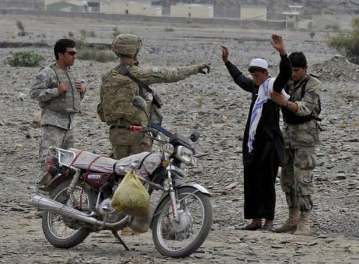 US soldiers watch as an Afghan soldier (R) searches a youth in the Turkham Nangarhar border region with Pakistan. Pakistan Wednesday rejected accusations that it was secretly supporting Taliban insurgents in Afghanistan, while the Taliban denied plans for peace talks with the Afghan government in Saudi Arabia