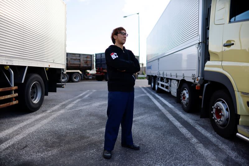 A truck driver Yuichi Tomita poses for a photograph next to his truck during his delivery work at a parking area along the highway in Chiba