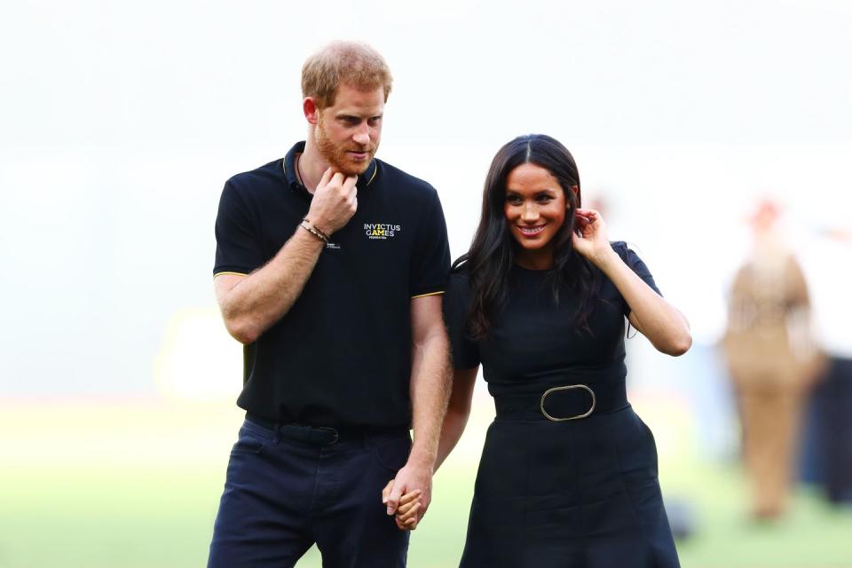 Prince Harry and Meghan Markle hold hands on the pitch.