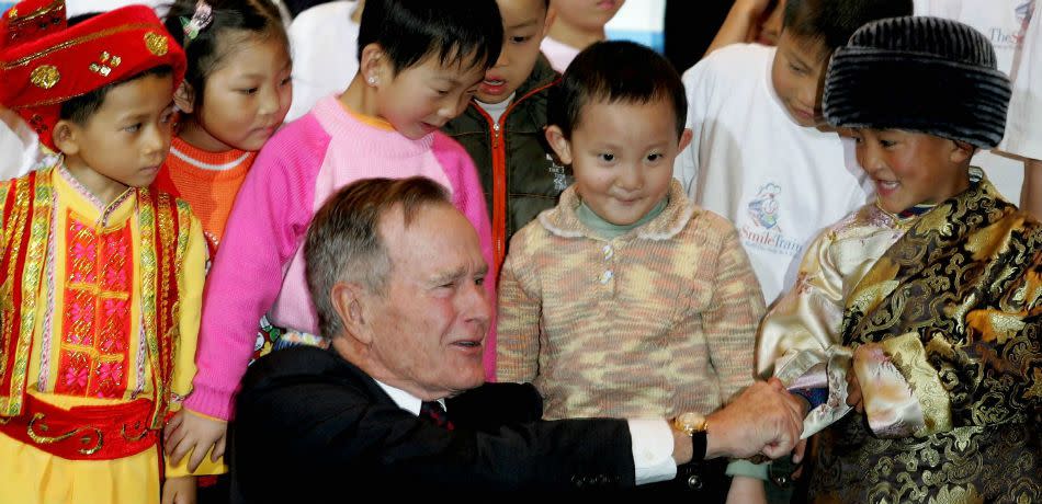 Former President George H.W. Bush shakes hands with young children in China that have received cleft lip surgery through Simle Train on November 15, 2005.