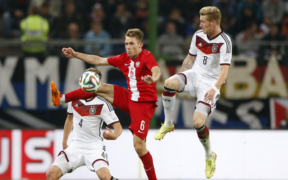 Germany's Andre Hahn, right, teammate Germany's Benedikt Hoewedes, background left, and Poland's Maciej Rybus challenge for the ball during a friendly soccer match between Germany and Poland in Hamburg, Germany, Tuesday, May 13, 2014. (AP Photo/Matthias Schrader)