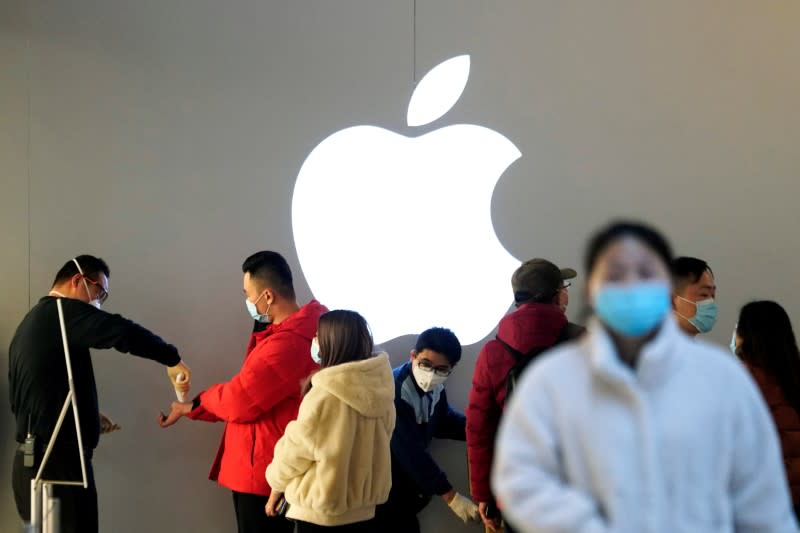 FILE PHOTO: People wearing protective masks wait for checking their temperature in an Apple Store, in Shanghai