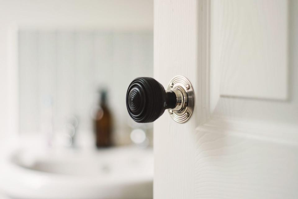 White door with black round door handle opening into a bathroom