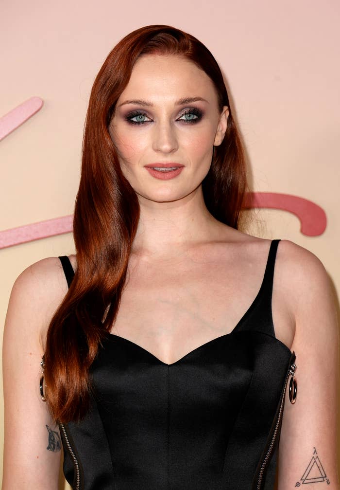 Sophie Turner in a dark outfit with sleek hair at an event