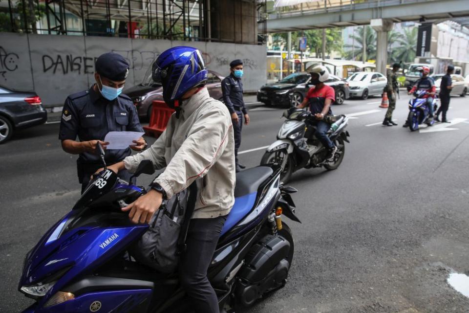 A policeman inspects a motorist’s travel documents during a roadblock on Jalan Syed Putra in Kuala Lumpur October 14, 2020. — Picture by Yusof Mat Isa