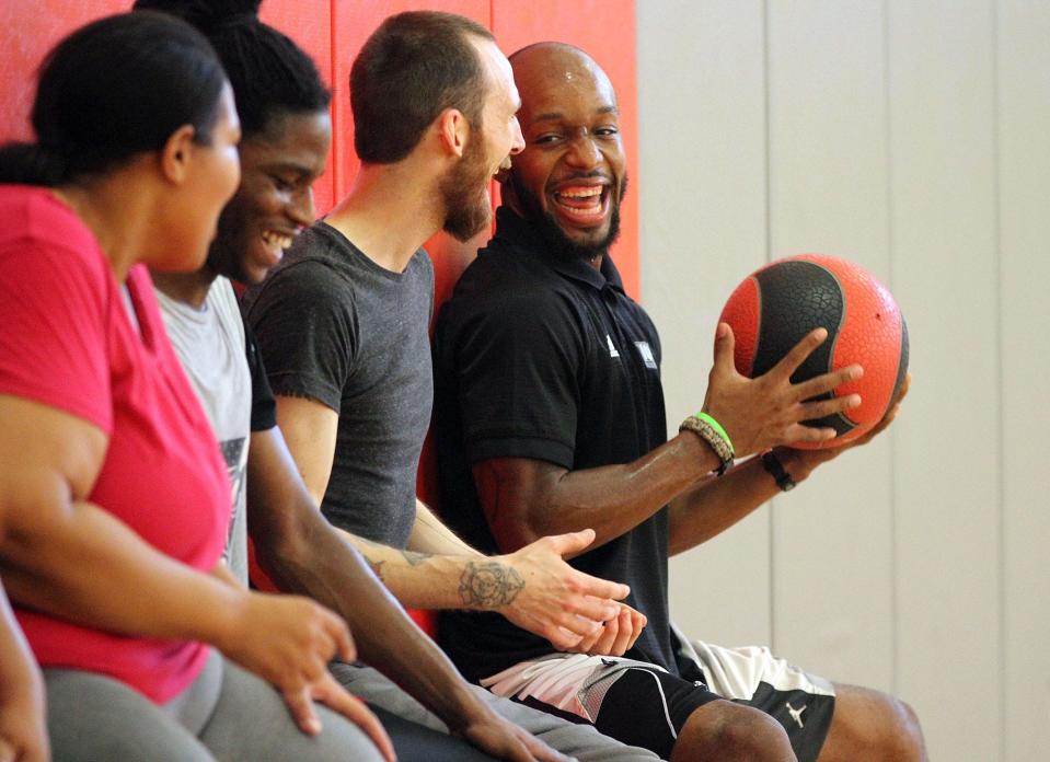Shawn Dyer, right, passes a weighted ball down a line of squatting students during a "Live Again" life fitness class at Harding High School in 2015. Shawn and his sister Shawntá hosted a 4-day youth basketball camp at Harding this summer. Both are part of the 30th induction class for the Marion Harding High School Athletic Hall of Fame.
