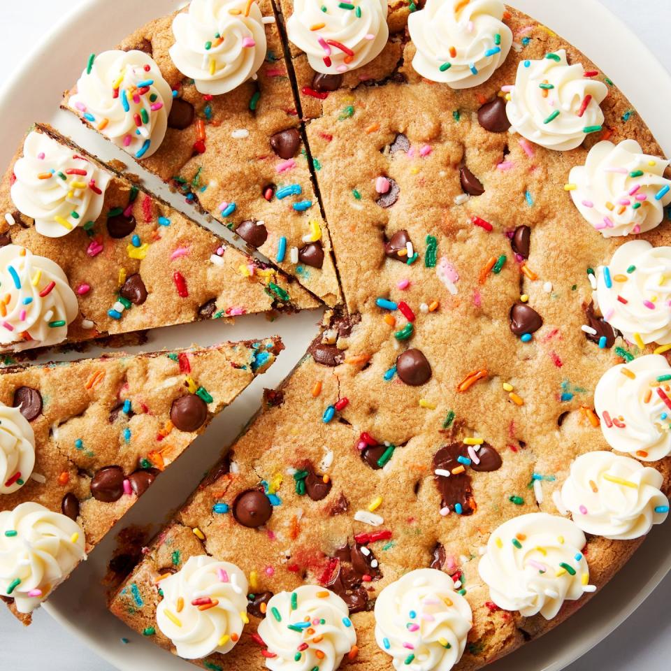 chocolate chip cookie cake topped with frosting swirls and sprinkles