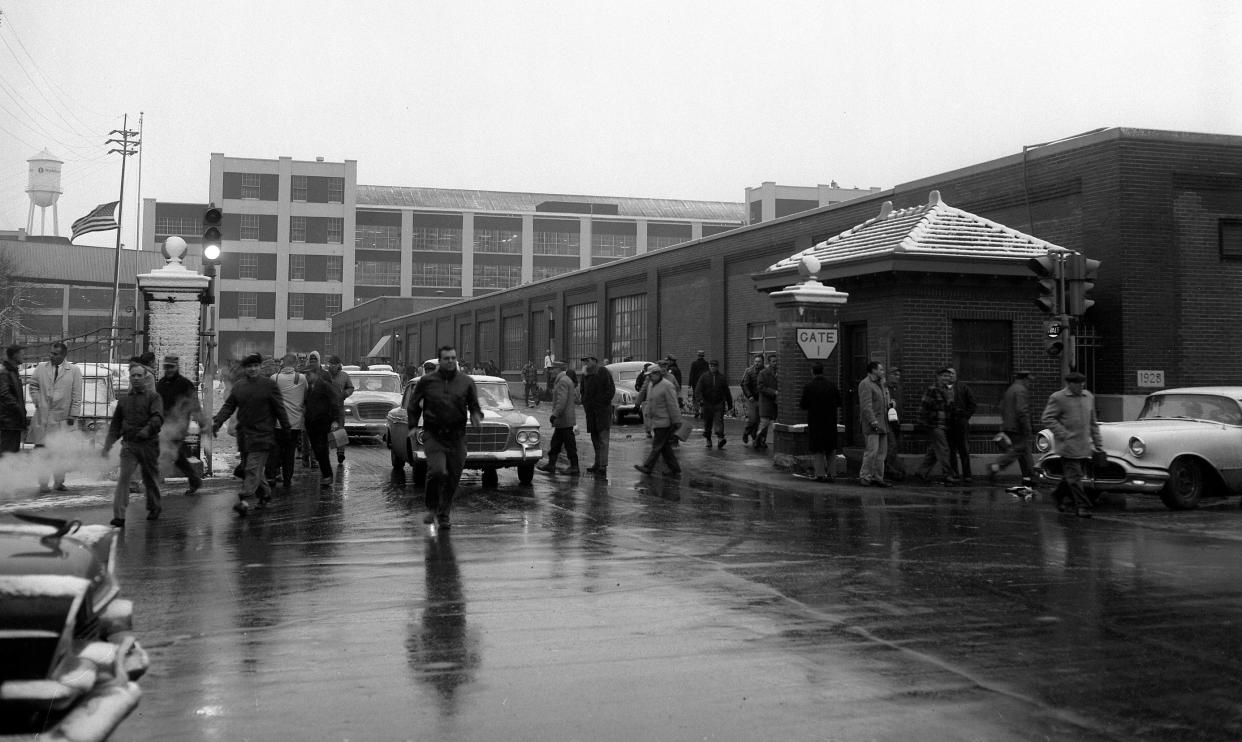Studebaker employees emerge through Gate 1 on Sample Street at 3:30 p.m. Monday, Dec. 9, 1963, at the end of their shift shortly after company officials in New York City confirmed news stories that automotive production in South Bend would be shifted to the corporation's Hamilton, Ont., plant in Canada. Newsmen were waiting at plant gates to interview workers. The company had refused newsmen permission to enter the plant for photos and interviews. The last car is produced in South Bend on Dec. 20. The American flag, upper left, flies in mourning for President John F. Kennedy.