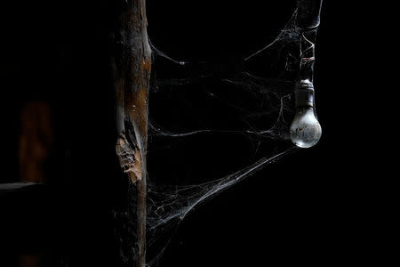 A bulb covered with cobwebs hangs inside a house at a minority village destroyed in the 2008 Sichuan earthquake on a mountain in Wenchuan county, Sichuan province, China, April 5, 2018. REUTERS/Jason Lee