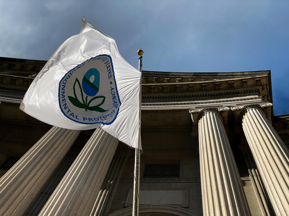 Flag of the Environmental Protection Agency viewed from below against the rising Ionic columns supporting the pediment of a building demonstrating classical Greek architecture.