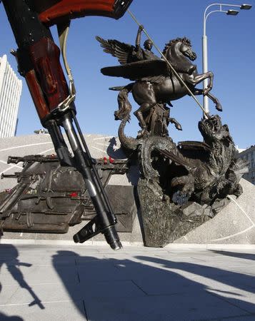 A view shows a monument to Russian inventor of the AK-47 assault rifle Mikhail Kalashnikov, as a man holds an object resembling a rifle designed by Kalashnikov nearby, in Moscow, Russia September 22, 2017. REUTERS/Sergei Karpukhin