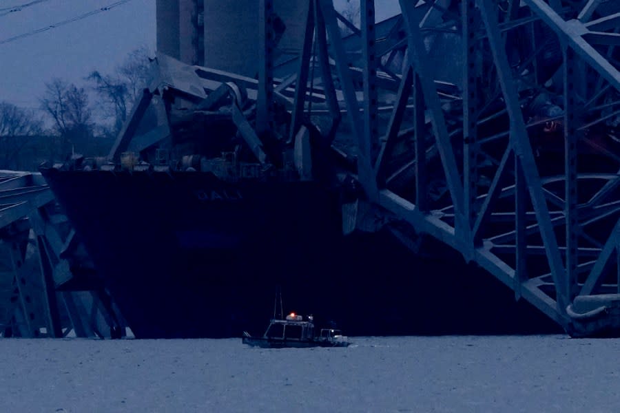 A container ship rests against wreckage of the Francis Scott Key Bridge as night falls on Tuesday, March 26, 2024, as seen from Sparrows Point, Md. The ship rammed into the major bridge in Baltimore early Tuesday, causing it to collapse in a matter of seconds and creating a terrifying scene as several vehicles plunged into the chilly river below. (AP Photo/Matt Rourke)