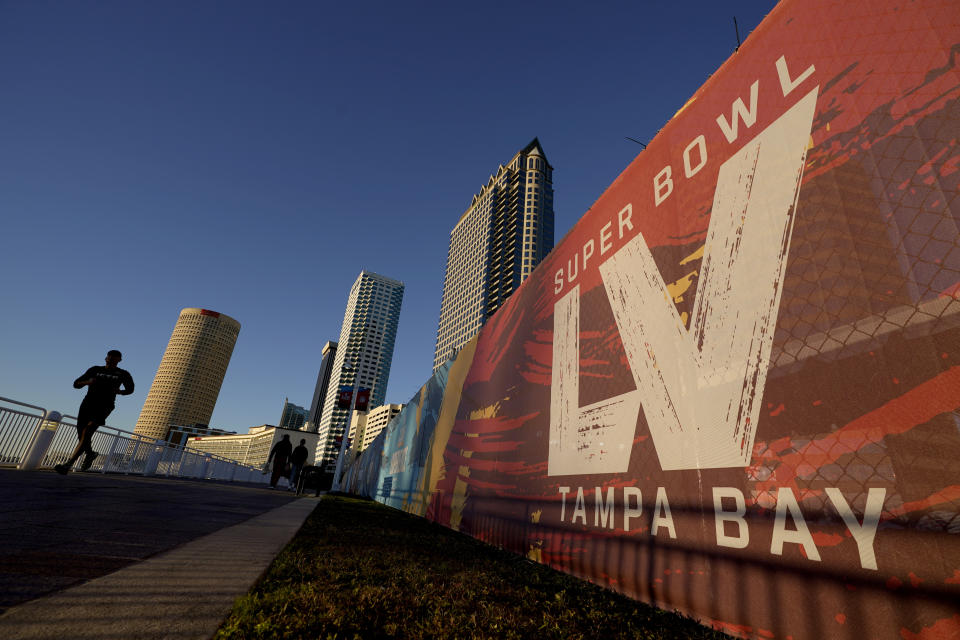 A man passes signage for Super Bowl 55 as he runs along the Hillsborough River on Wednesday, Feb. 3, 2021, in Tampa, Fla. The city is hosting Sunday's Super Bowl football game between the Tampa Bay Buccaneers and the Kansas City Chiefs. (AP Photo/Charlie Riedel)
