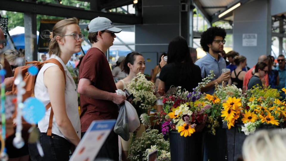 Farmers market attendees look at a vendor’s flower selection on Saturday, June 24, 2023 at Fifth Third Pavilion in Lexington, Ky.