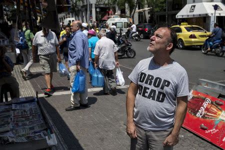 A man reads newspaper on a street in Athens, Greece, July 3, 2015. REUTERS/Marko Djurica