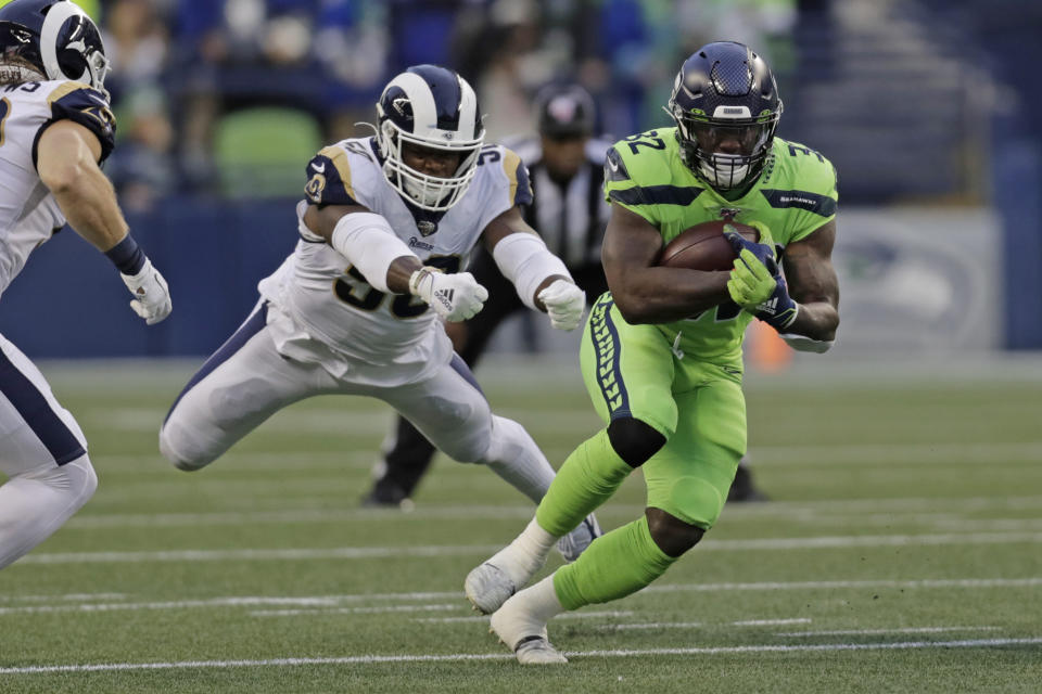 Seattle Seahawks running back Chris Carson, right, carries as Los Angeles Rams outside linebacker Samson Ebukam, left, leaps to attempt a tackle during the first half of an NFL football game Thursday, Oct. 3, 2019, in Seattle. (AP Photo/Stephen Brashear)
