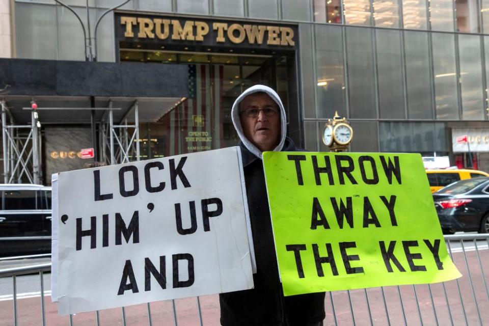 A man holds signs in front of Trump Tower on Fifth Avenue in New York on Friday.