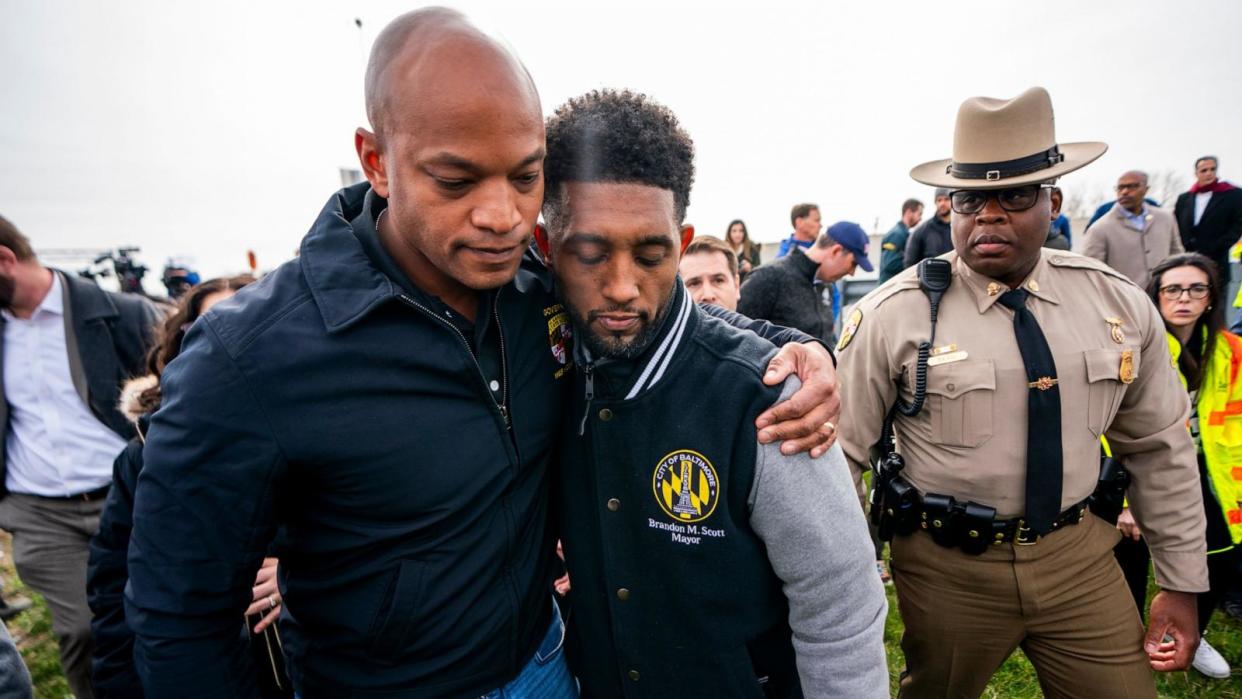 PHOTO: Maryland Governor Wes Moore (L) and Baltimore Mayor Brandon Scott embrace following a press conference at the scene of the Francis Scott Key Bridge collapse in Baltimore, Md, Mar. 26, 2024.  (Shawn Thew/EPA-EFE/Shutterstock)
