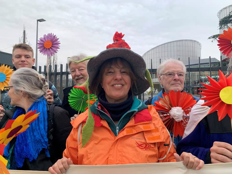 A female supporter smiles while holding a banner in support of the Senior Women for Climate Protection in front of the European Court of Human Rights in Strasbourg