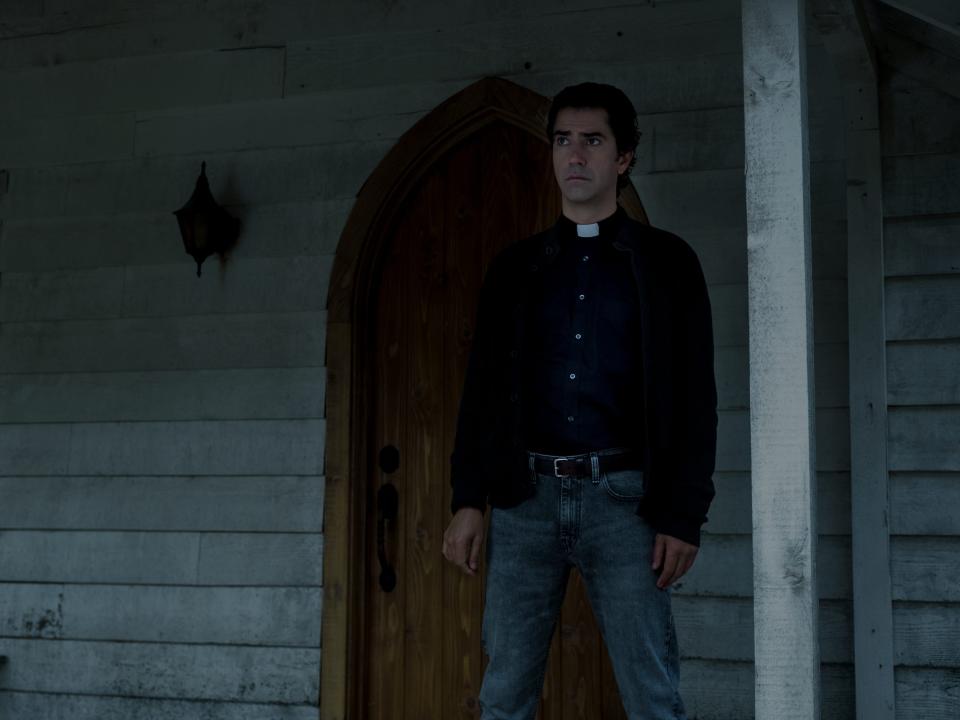 father paul standing on a front porch on midnight mass on netflix