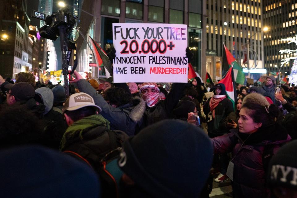 A protestor holding a sign at the ongoing holiday celebration in NYC (Getty Images)