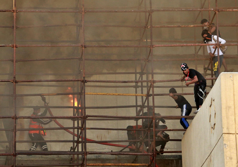 Anti-government protesters escape from a burning building during a demonstration in Baghdad, Iraq, Saturday, Oct. 26, 2019. (Photo: Hadi Mizban/AP)