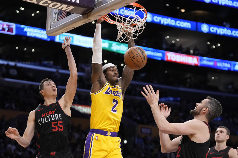 Los Angeles Lakers forward Jarred Vanderbilt, center, dunks as Miami Heat forward Duncan Robinson, left, and forward Kevin Love defend during the first half of an NBA basketball game Wednesday, Jan. 3, 2024, in Los Angeles. (AP Photo/Mark J. Terrill)