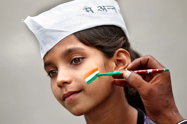 A man paints the tri-colours of India's national flag on the face of a supporter of veteran Indian social activist Anna Hazare on the first day of Hazare's fast against corruption in New Delhi, July 29, 2012. Hazare began his fast on Sunday to demand a bill, the Lokpal, for creating an autonomous, powerful anti-corruption agency. REUTERS/Adnan Abidi