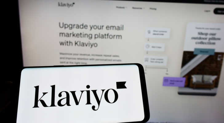 Person holding cellphone with logo of US marketing software company Klaviyo Inc. (KVYO) on screen in front of business webpage. Focus on phone display. Unmodified photo.