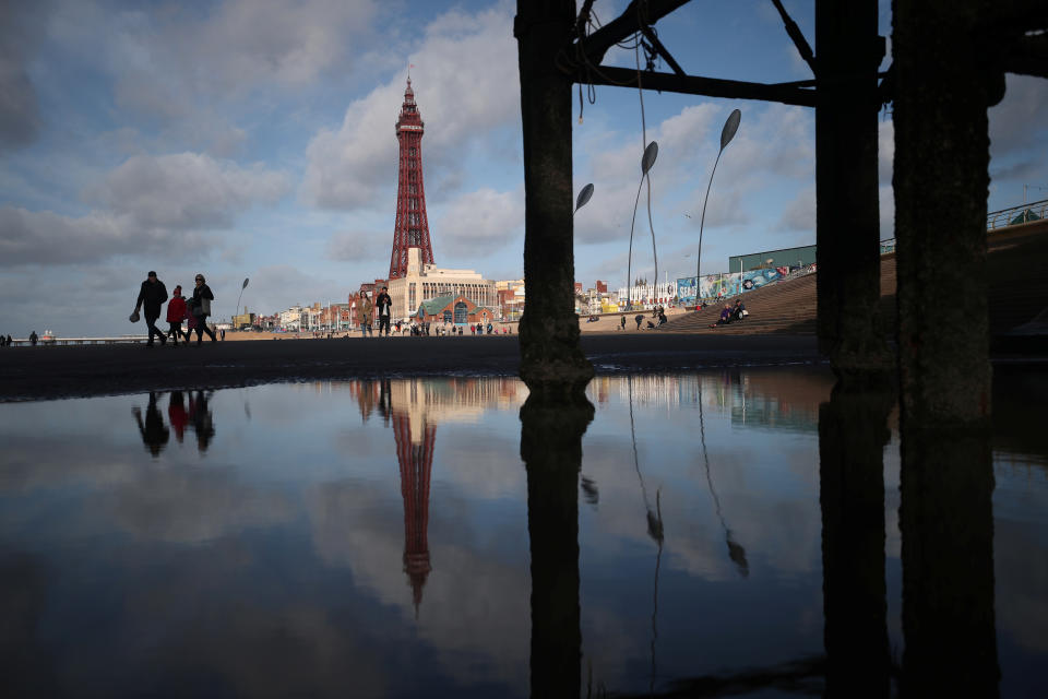 People walk along the beach as the Blackpool Tower is reflected in a pool under the pier, in Blackpool, Britain, October 22, 2018. REUTERS/Hannah McKay