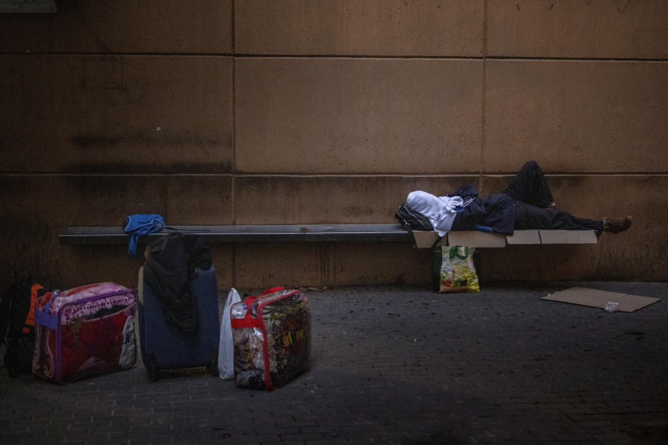 A man with his face covered with towel, sleeps in a square in Lleida, Spain, Thursday, July 2, 2020. Authorities in northeast Spain have ordered the lockdown of a county around the city of Lleida due to worrying outbreaks of the COVID-19 virus. Catalan regional authorities announced Saturday, July 4, 2020 that as of noon local time movement will be restricted to and from the county of El Segriá around Lleida which is home to over 200,000 people. Residents will have until 4 p.m. to enter the area. The new outbreaks are linked to agricultural workers in the rural area. (AP Photo/Emilio Morenatti)