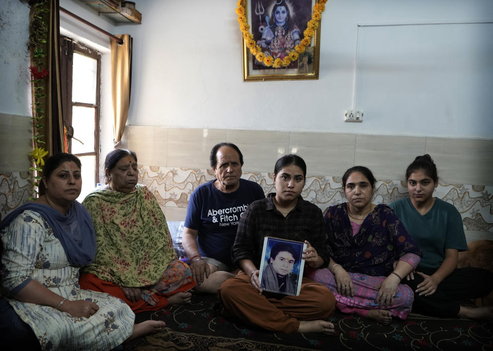 Family members sit with a portrait of Ajay Pandita Bharti, a Kashmiri Hindu village head who was shot dead in Kashmir, at their residence in Jammu, India, June 14, 2022. Kashmir has witnessed a spate of targeted killings in recent months. Several Hindus, including immigrant workers from Indian states, have been killed. (AP Photo/Channi Anand)