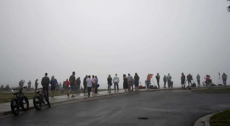 Spectators stand in the fog to try and view the test launch of SpaceX rocket flight SN11