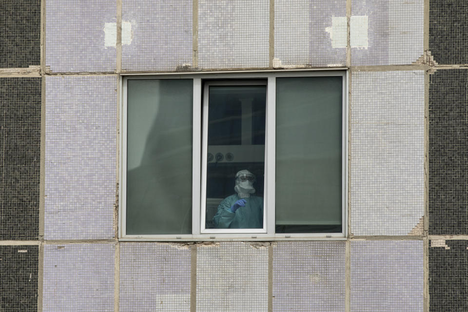 Un sanitario con mascarilla y equipo protector mira por la ventana del Hospital La Paz de Madrid. (Foto: Pablo Blazquez Dominguez / Getty Images).