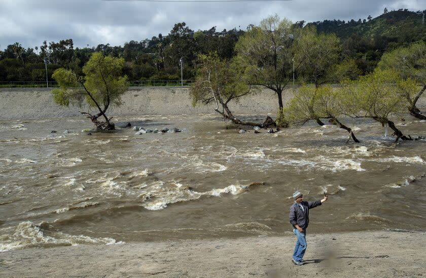 LOS ANGELES, CA-MARCH 29, 2023: David Jannesn, 49, takes a selfie next to the raging Los Angeles river near Los Feliz Blvd. In Los Angeles, during a break from the rain. (Mel Melcon / Los Angeles Times)