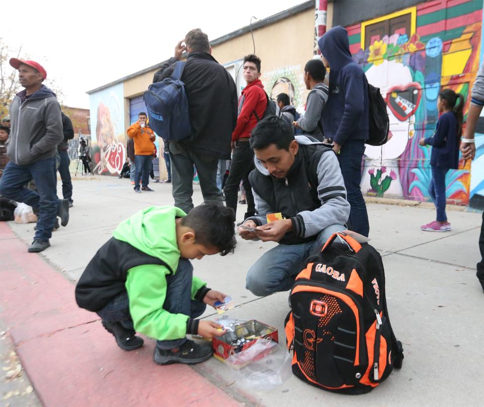 Jose Manuel Perez of Guatemala plays with his son, Sancer Perez, 9, outside the former Rock House Café and Gallery at Leon Street and Overland Avenue. Perez said they left Guatemala 12 days ago and plan to travel to Atlanta to join relatives there.