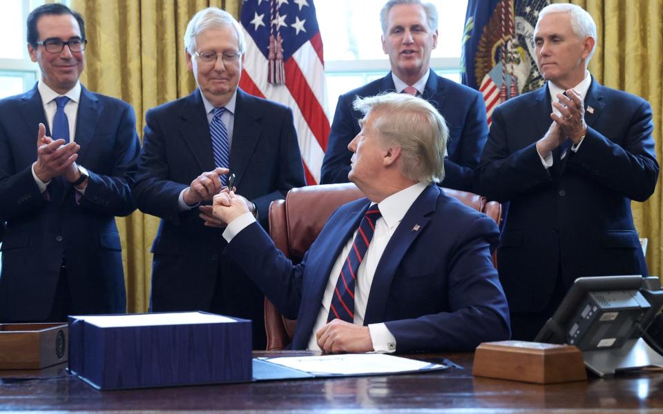 Donald Trump hands a pen to Senate Majority Leader Mitch McConnell after signing the $2.2 trillion coronavirus aid package bill during a signing ceremony in the Oval Office of the White House in Washington, U.S., March 27, 2020