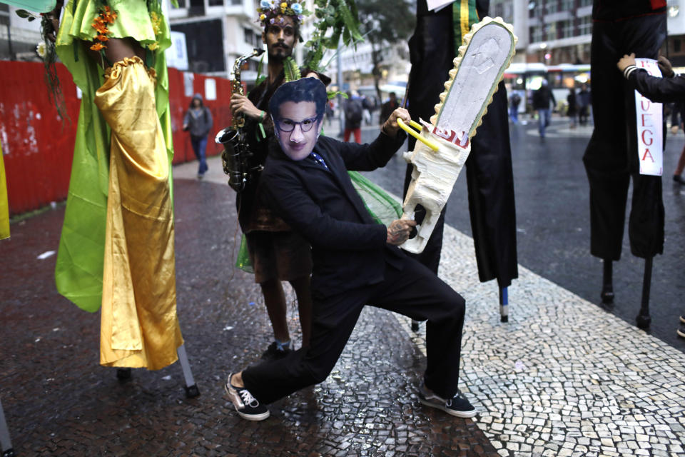A demonstrator wearing a mask with the likeness of Brazil's Environment Minister Ricardo Salles brandishing a fake chainsaw, participates in a protest to defend of the Amazon, in Rio de Janeiro, Brazil, Thursday, Sept. 5, 2019. The Brazilian Amazon saw almost 31 thousand fires in August, the highest for the month since 2010, according to Brazil's National Institute for Space Research. (AP Photo/Silvia Izquierdo)