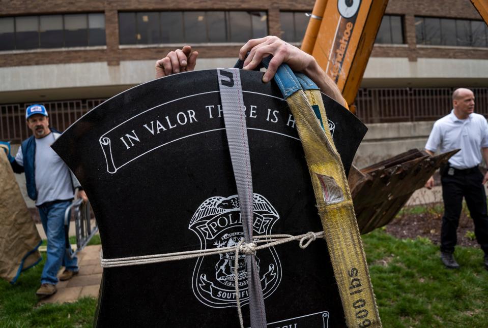 Ken Noseda, center, of J. Noseda & Son Inc., works to add a strap to lift the Southfield Police Department's "Fallen Hero" granite sculpture to a more visible spot outside the police station in Southfield on Wednesday, April 5, 2023.