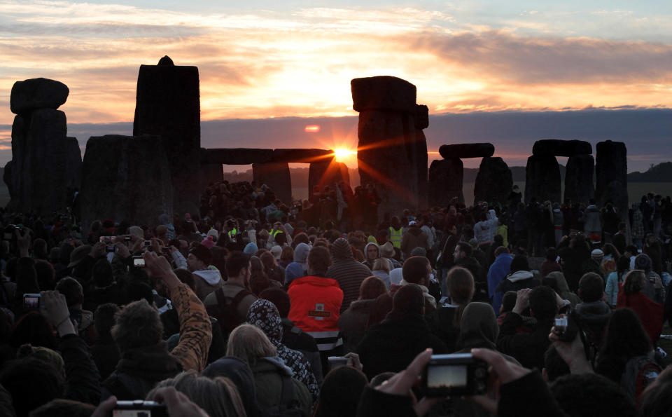 AMESBURY, ENGLAND - JUNE 21:  Revelers watch as the midsummer sun rises just after dawn over the megalithic monument of Stonehenge on June 21, 2010 on Salisbury Plain, England. (Photo by Matt Cardy/Getty Images)