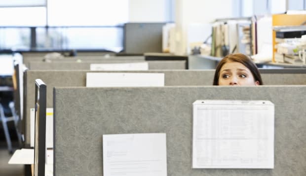 Worried office worker looking over top of cubicle