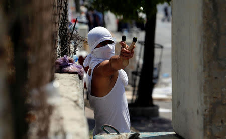 A Palestinian protester uses a slingshot to hurl stones towards Israeli troops during clashes in the West Bank city of Bethlehem July 21, 2017. REUTERS/Mussa Qawasma