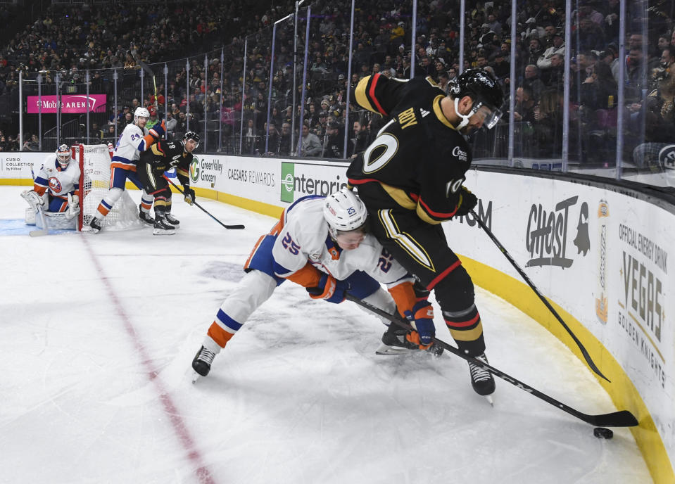 New York Islanders defenseman Sebastian Aho (25) and Vegas Golden Knights center Nicolas Roy (10) fight for the puck during the second period of an NHL hockey game Saturday, Dec. 17, 2022, in Las Vegas. (AP Photo/Sam Morris)