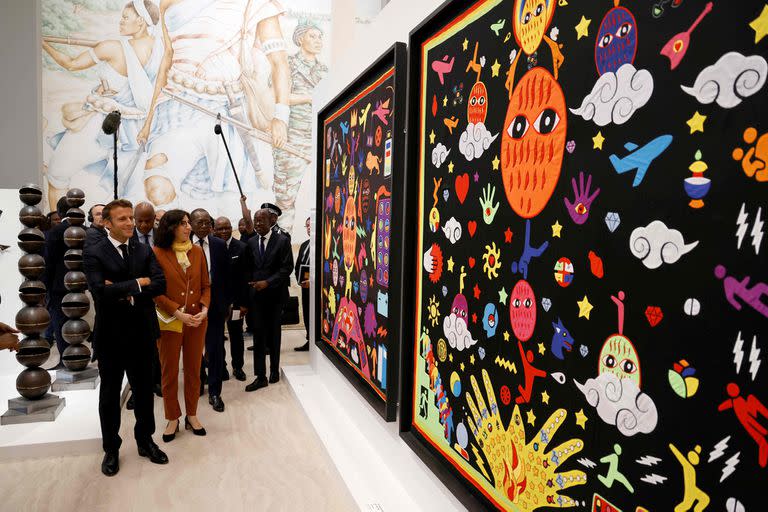 France's President Emmanuel Macron (L) and French Culture Minister Rima Abdul-Malak (2nd L) visit the "Contemporary Art of Benin" section of the exhibition "Benin Art of yesterday and today: from Restitution to Revelation" at the Marina Palace of Cotonou on July 27, 2022, as part of Macron's official visit in Benin. - The exhibition features Beninese contemporary artists pieces and the twenty-six royal treasures looted by the French colonial soldiers recently returned by France. (Photo by Ludovic MARIN / AFP)