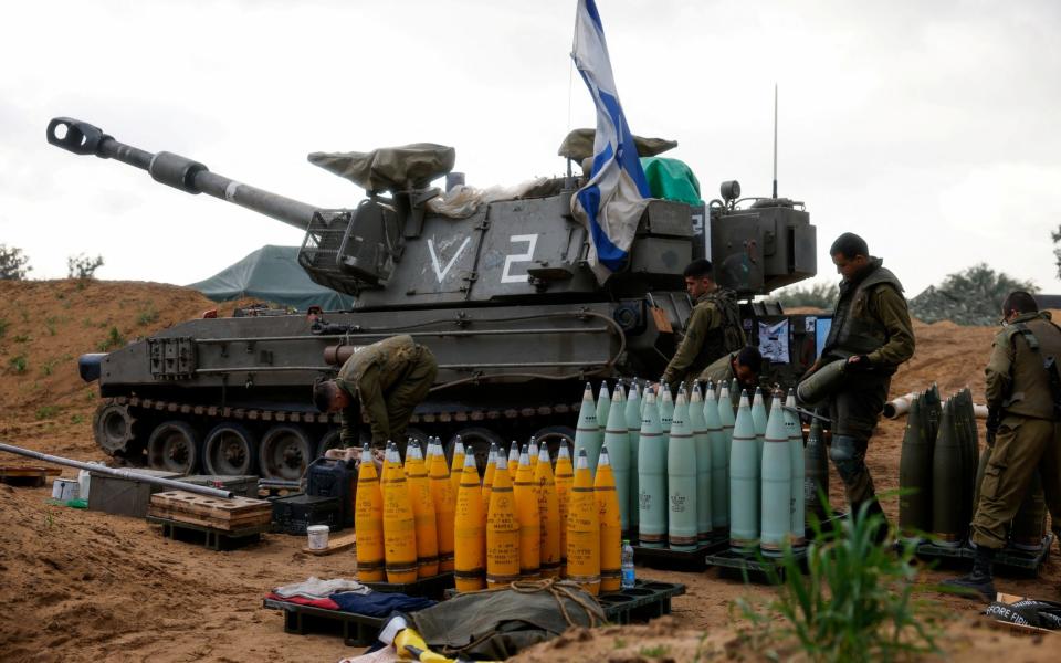 Israeli soldiers prepare shells near a mobile artillery unit, amid the ongoing conflict