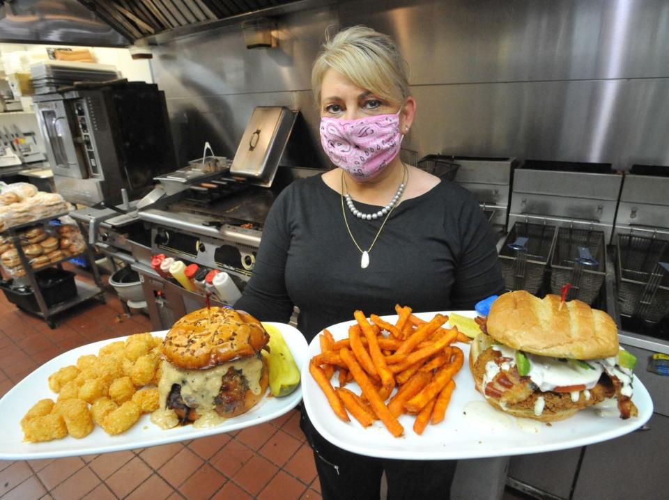 KKatie's Burger Bar co-owner Kate McSorley serves up a horseradish peppercorn burger, left, and a classic buttermilk chicken sandwich. (Tom Gorman/For The Patriot Ledger)